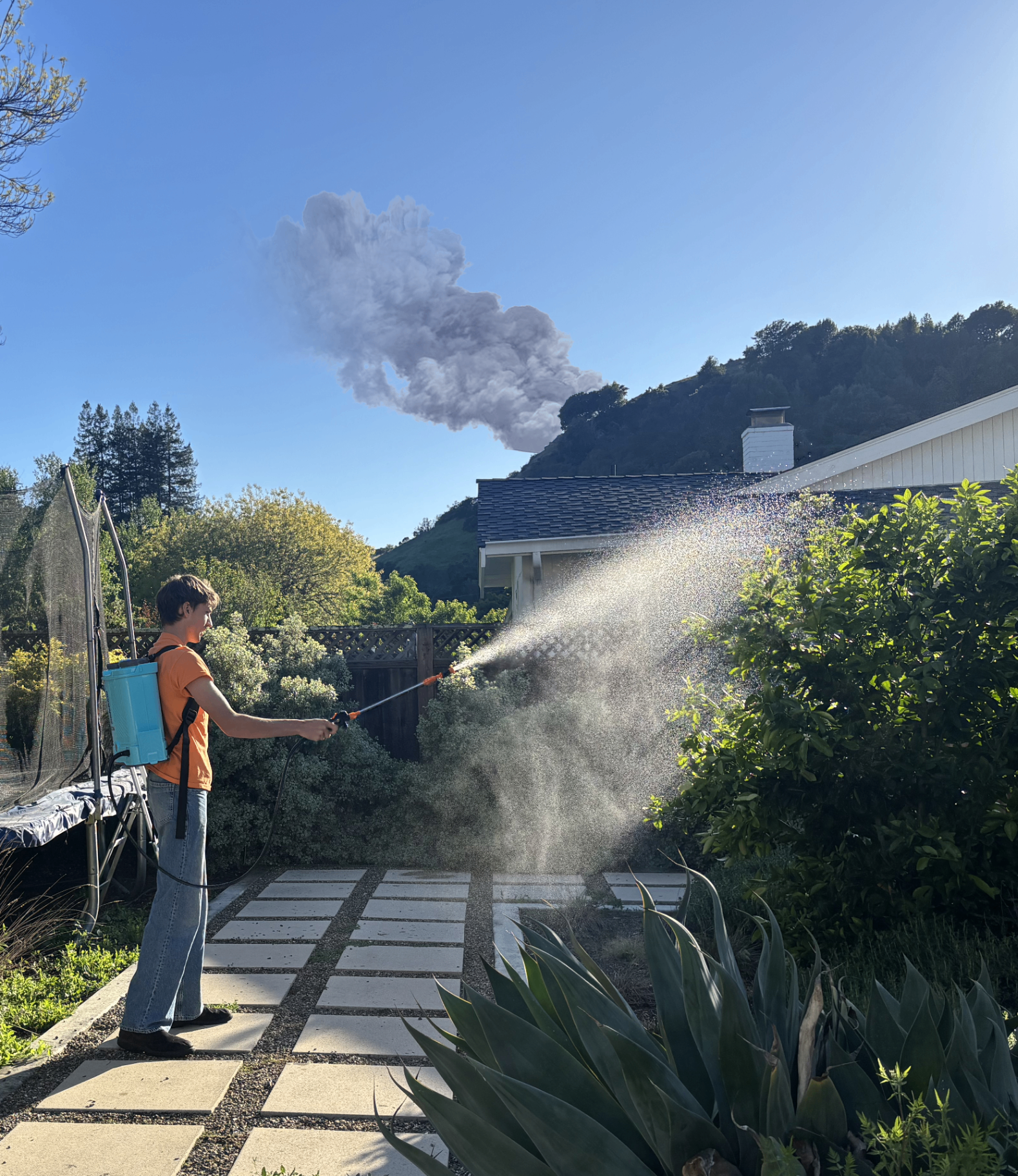 Homeowner applying Clore wildfire defense spray around their home